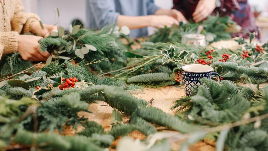 People crafting wreaths with greenery and berries.