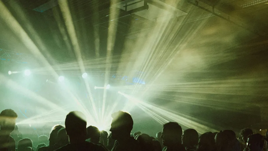 Silhouettes at a concert with bright stage lights.