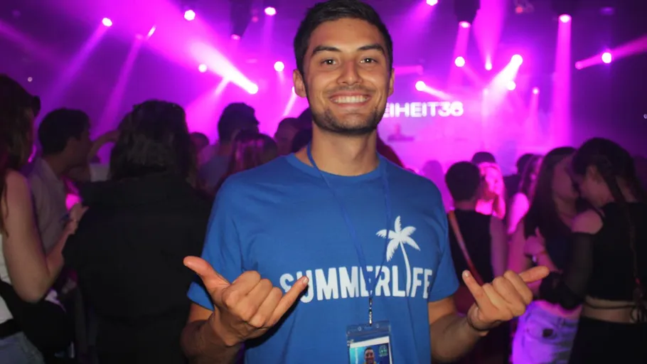 Man smiling at nightclub event, colorful lights.