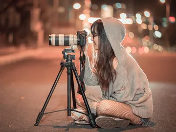 Photographer sitting on the street, concentrating on camera.