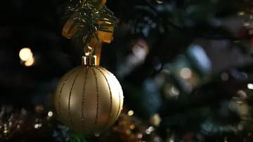 Gold ornament hanging on Christmas tree.
