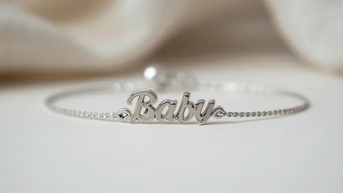 Silberarmband mit 'Baby'-Schrift auf Tisch.