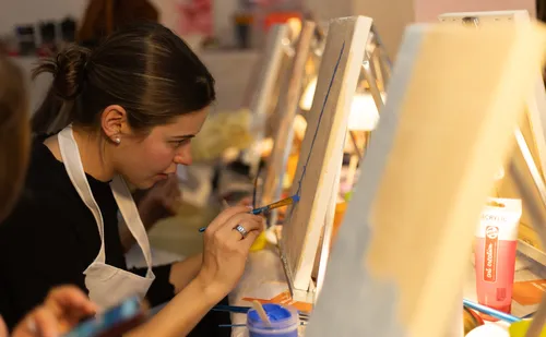 Woman painting on canvas in art class.