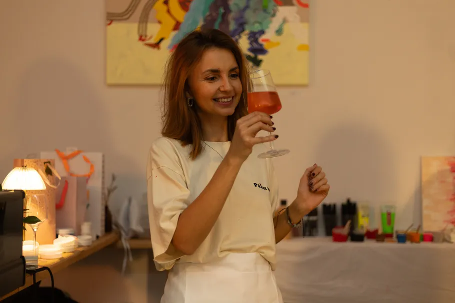 Woman holding drink, smiling in art studio.