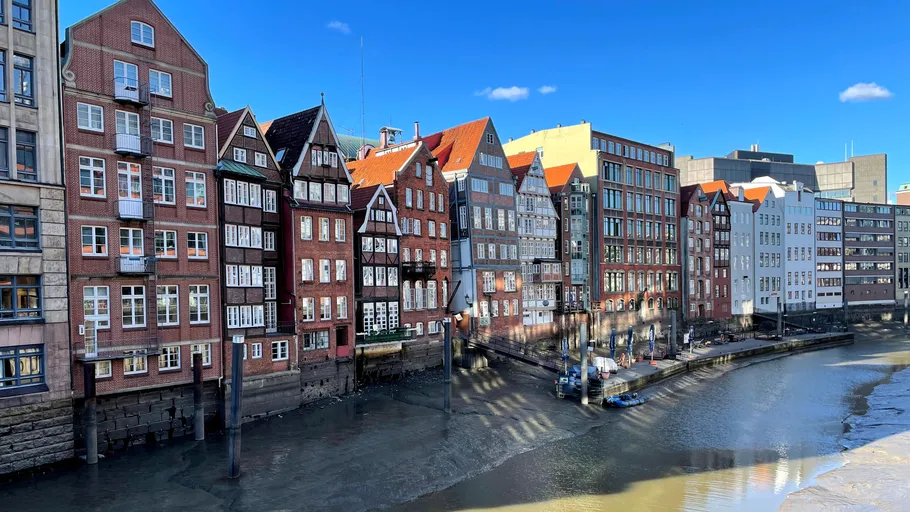 Historic buildings along canal under blue sky.