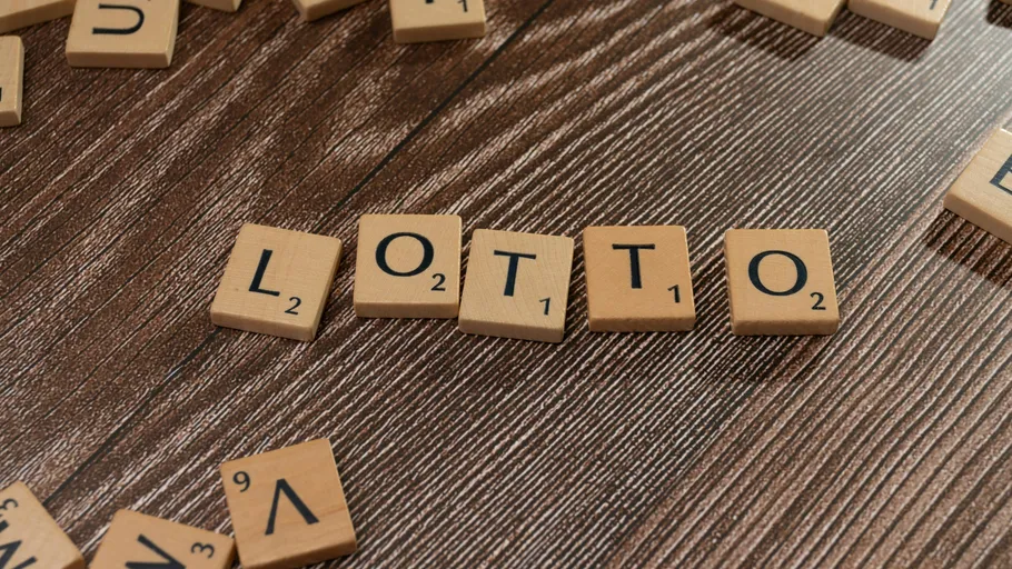 Scrabble tiles spell 'LOTTO' on wood surface.