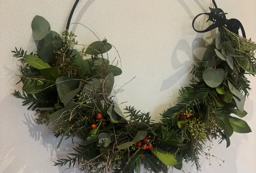 Green wreath hanging on a white wall.