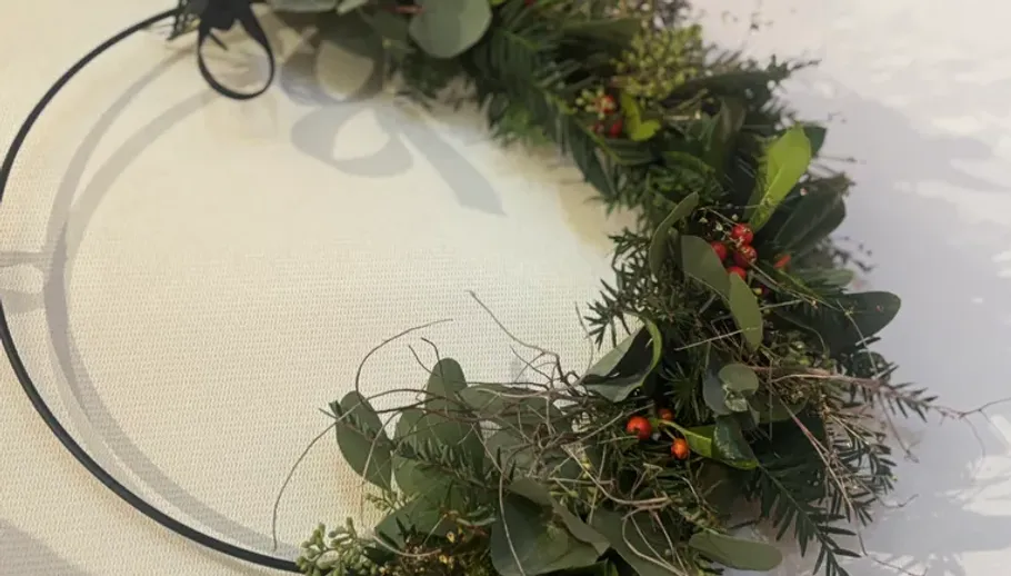 Green wreath with red berries on table.