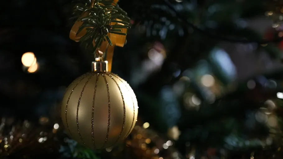 Goldener Schmuck hängt am Weihnachtsbaum.