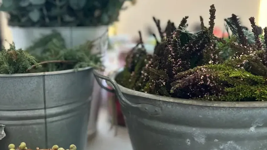 Metal buckets filled with foliage on table.