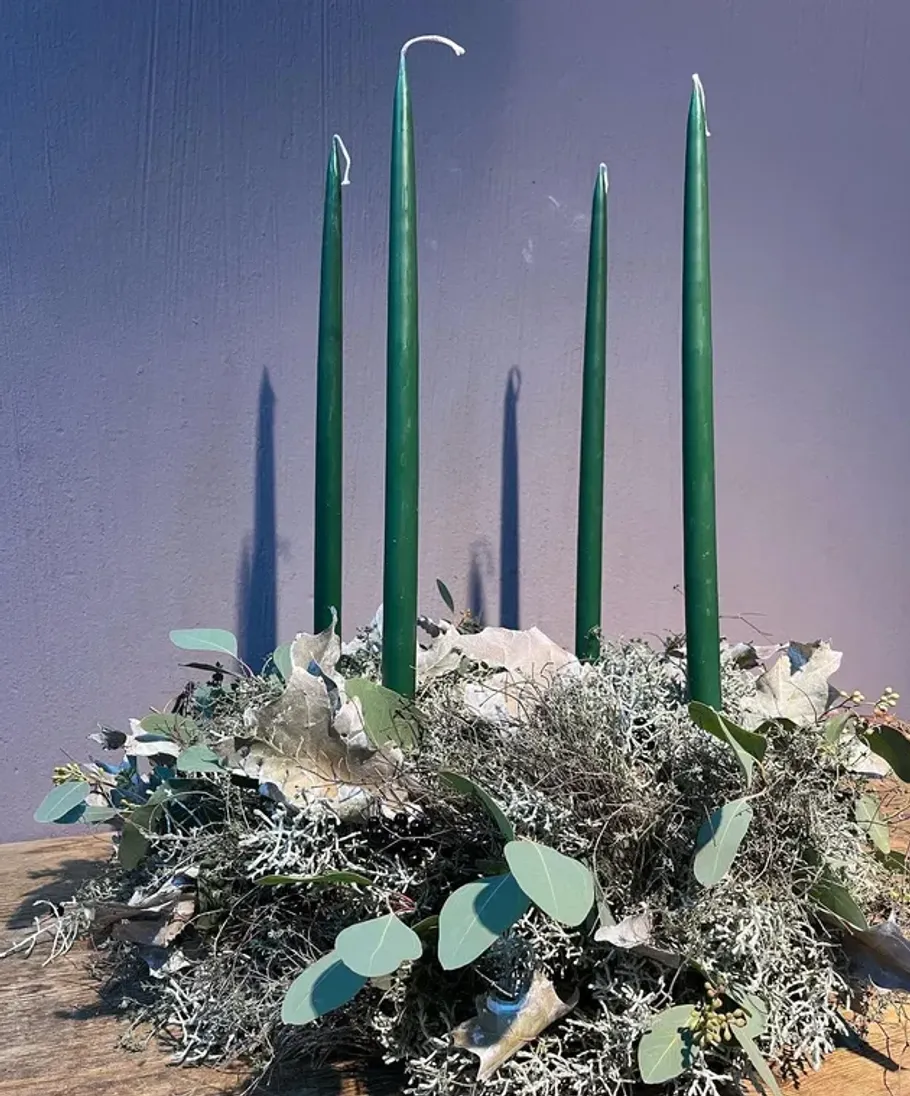 Green candles in a wreath on a table.