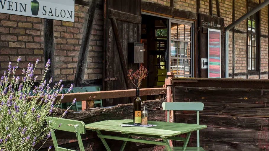 Outdoor table with wine bottle, rustic building.
