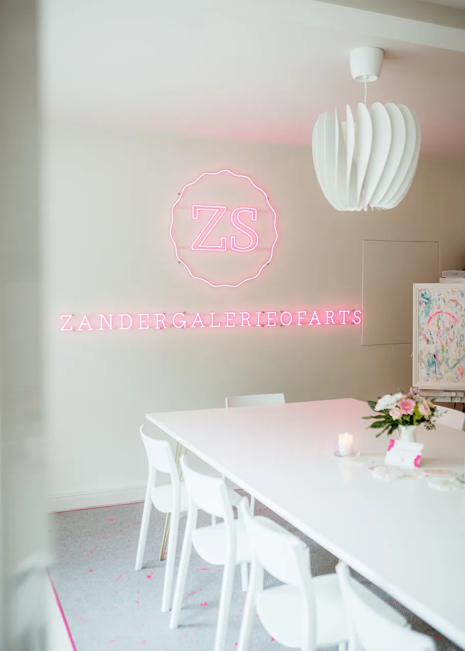 Neon sign above white table and chairs.