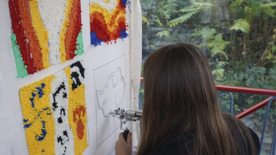 Person benutzt Tufting-Pistole auf Stoffdesign.