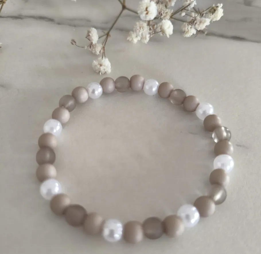 Beaded bracelet with white flowers nearby.