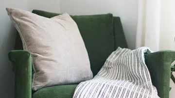 Green chair with cushion and blanket.