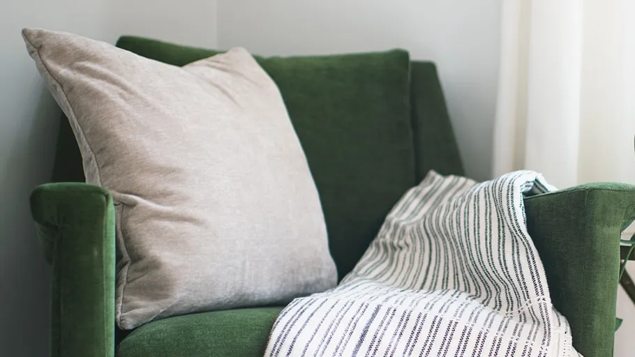 Green chair with cushion and blanket.
