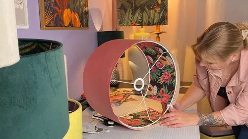 Woman crafting floral lampshade in studio.