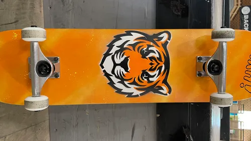 Orange skateboard with tiger face design.