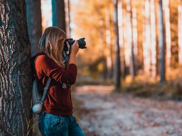 Eine Person fotografiert in einem herbstlichen Wald.