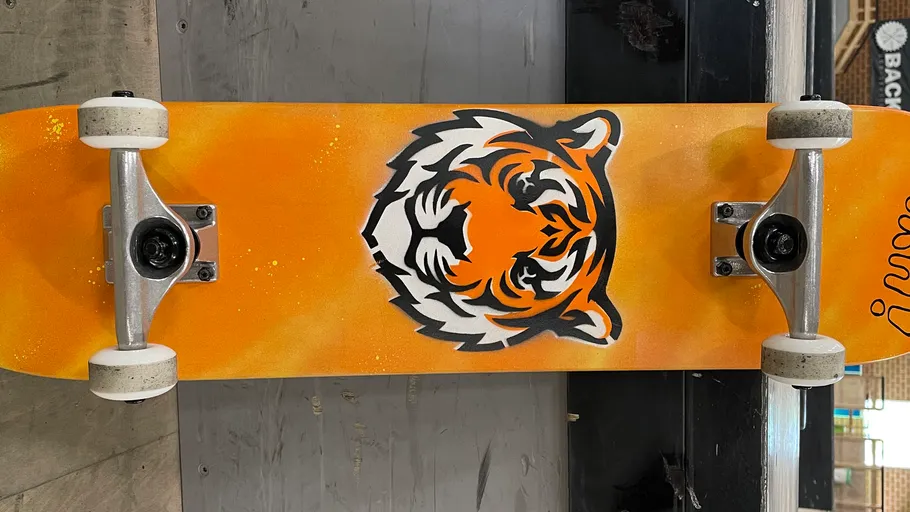 Skateboard with tiger design on orange background.