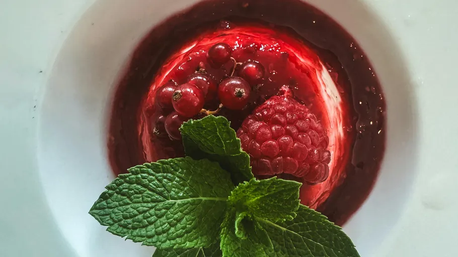 Raspberry dessert with mint garnish on plate.