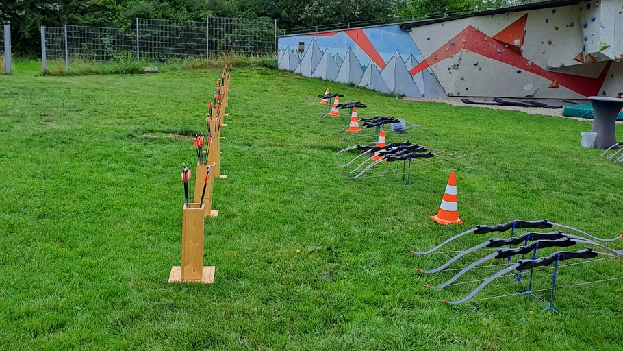 Bows and arrows lined up on grass.
