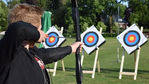Person aiming bow at archery targets outdoors.