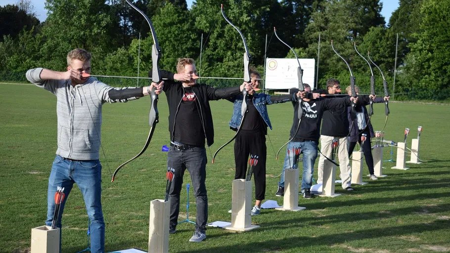 Six people aiming bows on a field.