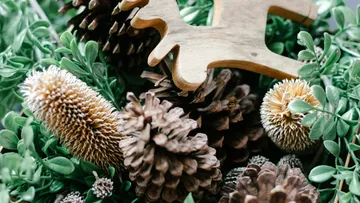 Pinecones and wooden reindeer among greenery.