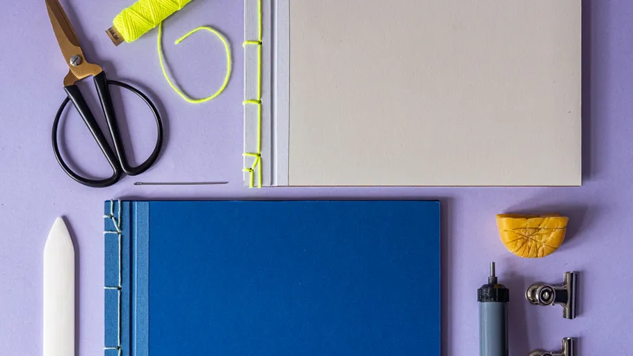 Notebooks with binding tools on purple surface.