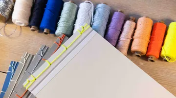 Colorful threads and bound books on table.