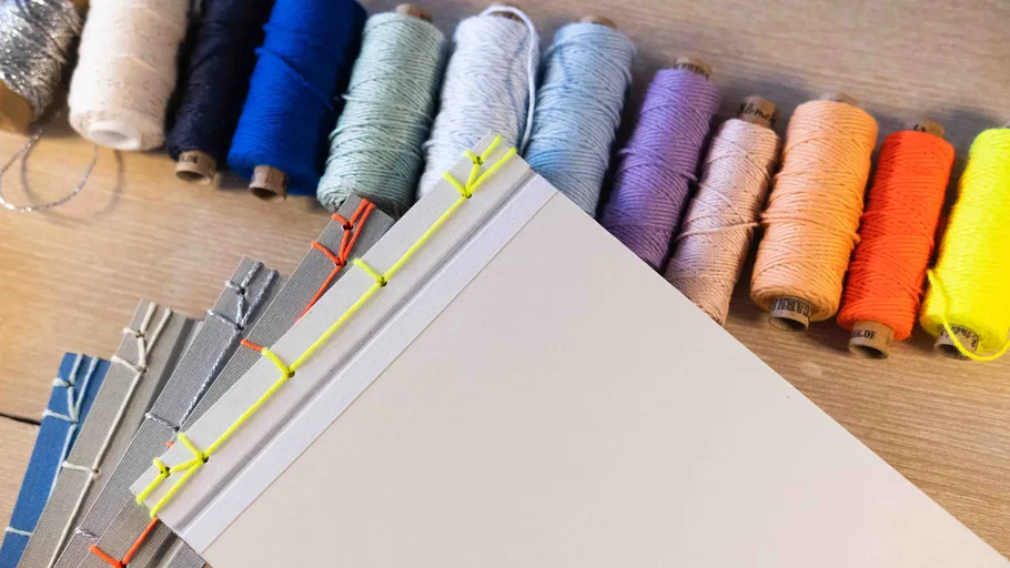 Colorful threads and bound books on table.