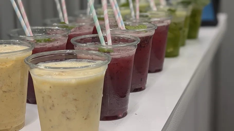 Various colorful drinks with paper straws on table.