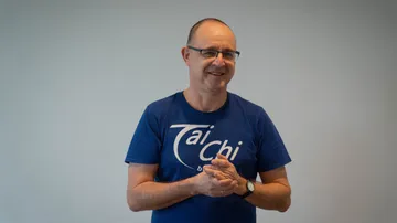 Mann im blauen Shirt lächelt drinnen.