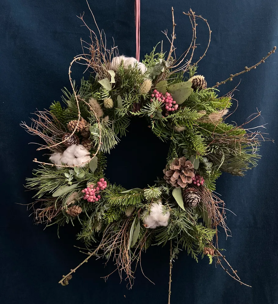 Decorative wreath with pinecones on dark background.