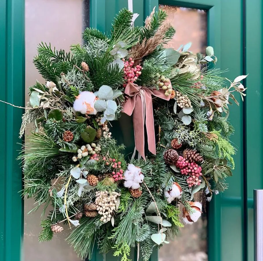 Decorative wreath hanging on green door.