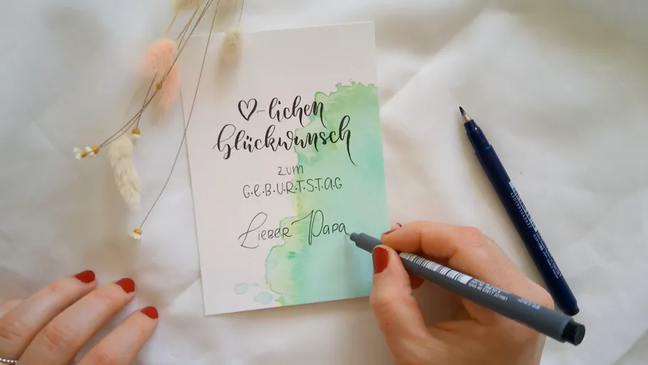 Handwriting on birthday card with flowers nearby.