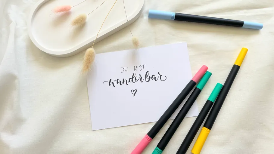 Card with pens on white fabric background.