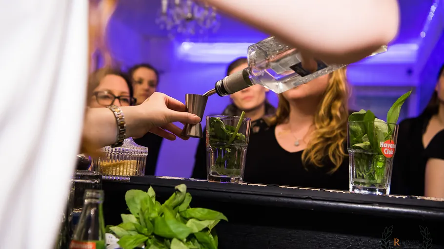 Person gießt Alkohol in einen Messbecher an einer Bar.