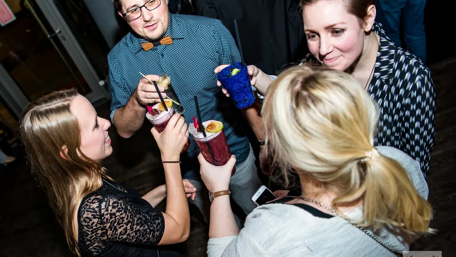 Vier Personen stoßen mit Cocktails drinnen an.