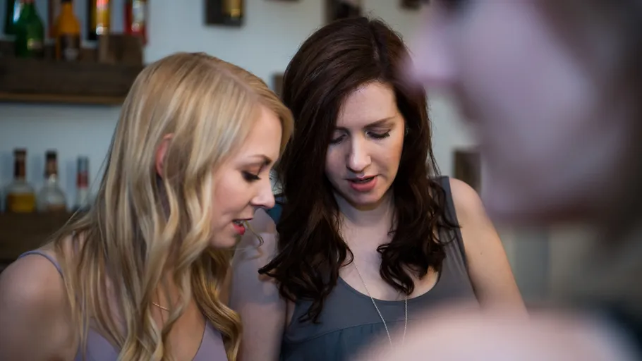 Two women talking in a bar setting.