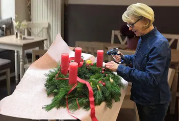 Frau dekoriert Kranz mit Kerzen im Raum.