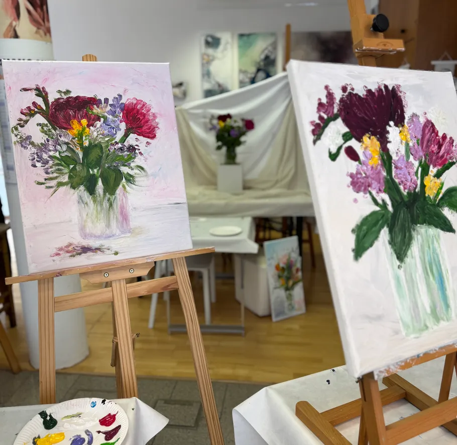 Two floral paintings on easels in an art studio.