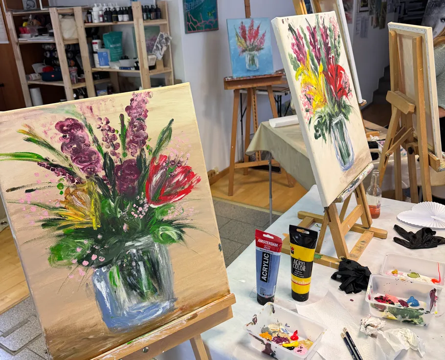 Paintings of flowers on easels in studio.