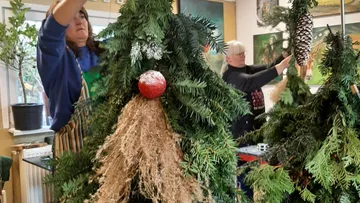 Women decorating Christmas tree indoors.