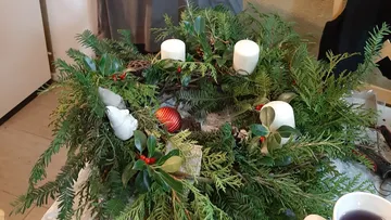 Christmas wreath with candles and greenery indoors.