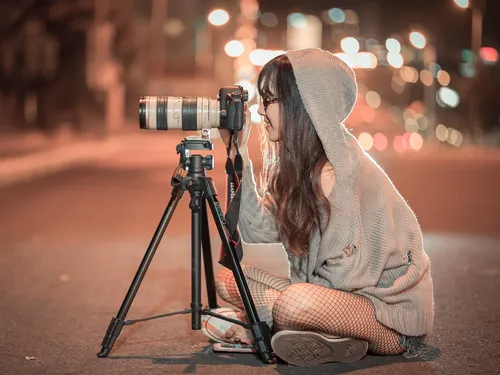 A photographer sits on the street and takes pictures.