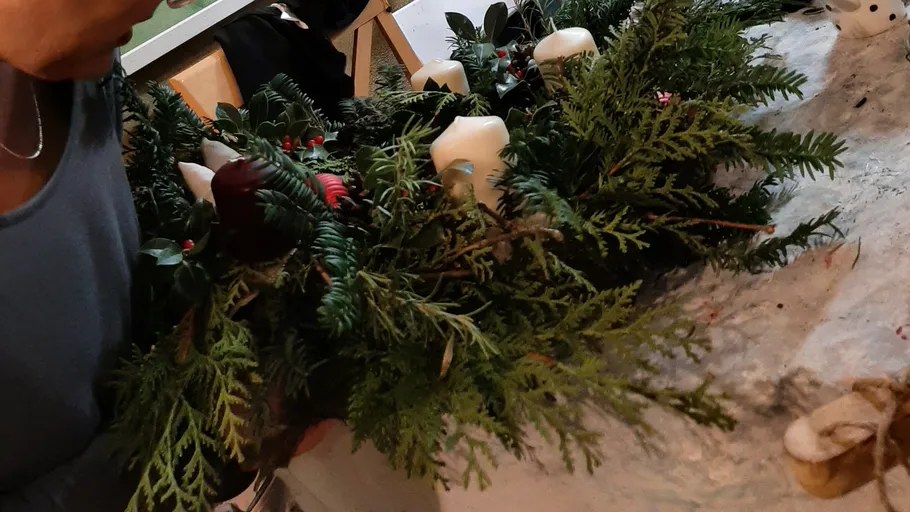 Person bastelt Kranz mit Kerzen im Innenraum.