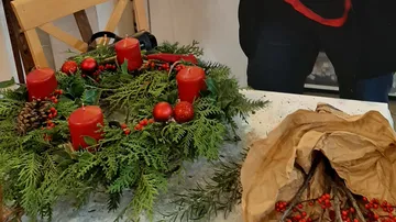 Festlicher Kranz mit roten Kerzen auf Tisch.